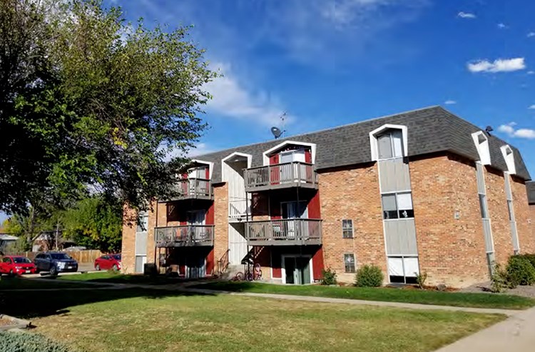 a brick apartment building with balconies and a blue sky