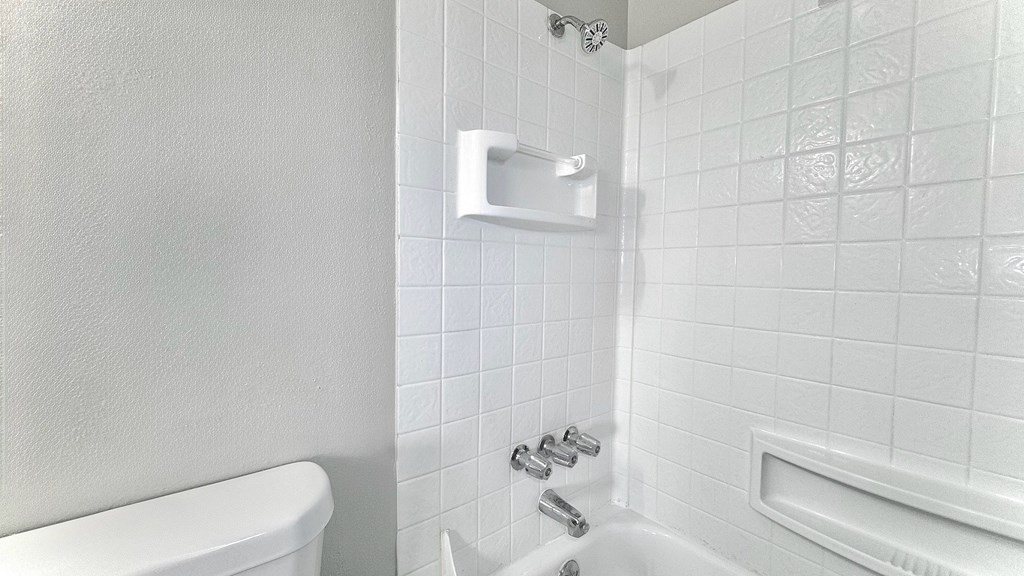A white bathroom with a tub, shower, and tiled walls.