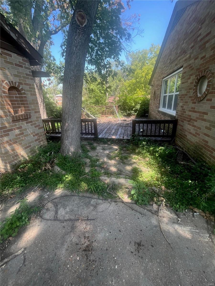 the backyard of a brick house with a tree and a pathway