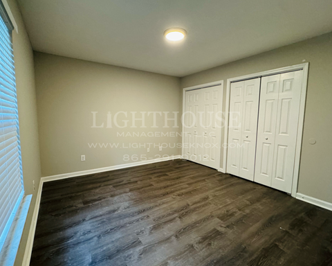 a bedroom with three closets and wood flooring