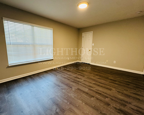 a bedroom with a large window and wood floors