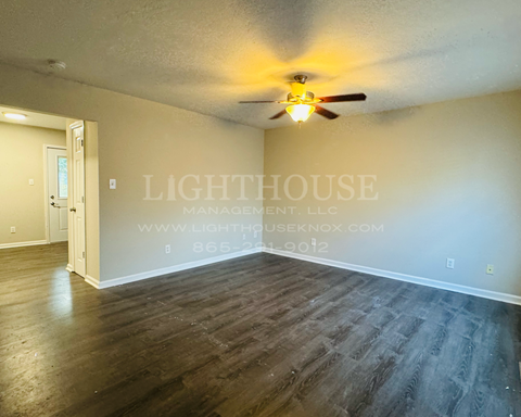 an empty living room with wood floors and a ceiling fan
