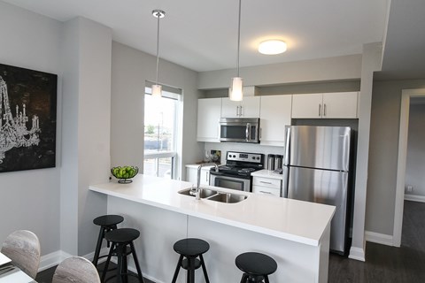 A modern kitchen with a white island and stools.