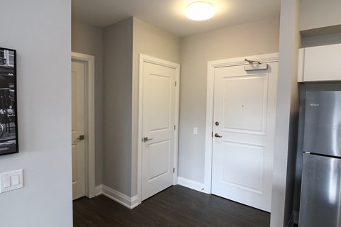 A kitchen with a refrigerator on the right and three doors.