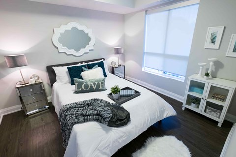 A bedroom with a white bed and a mirror on the wall.