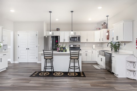 a kitchen with white cabinets and a island with two chairs