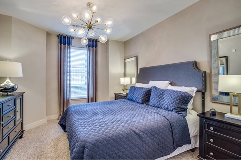 A bedroom with a large bed and a chandelier.
