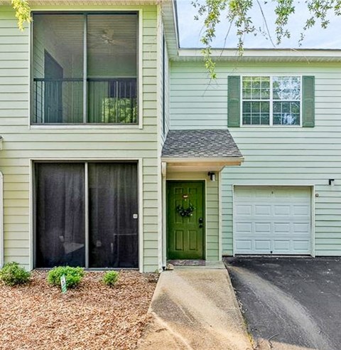 a white house with a green door and a driveway