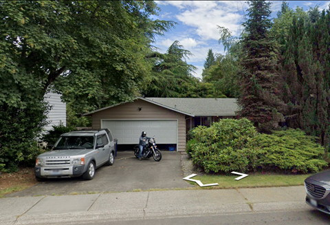 A silver truck is parked in front of a garage.