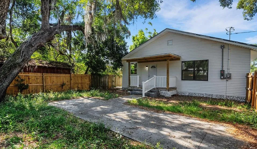 a white house with a wooden fence and a driveway