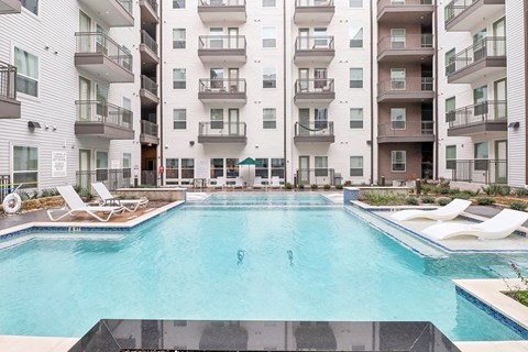 A large swimming pool in front of apartment buildings.