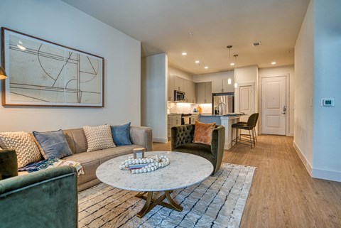 a living room with couches and a coffee table in front of a kitchen
