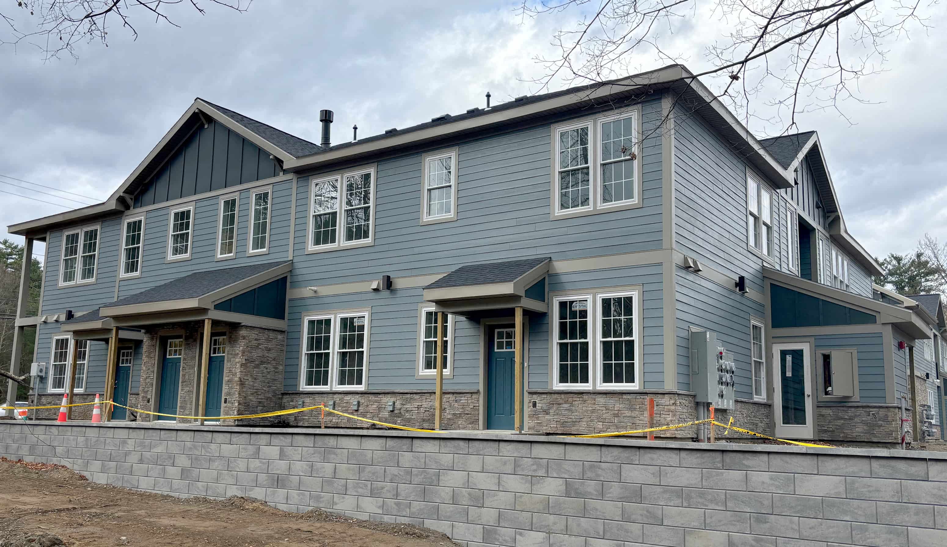 a large blue house with a stone retaining wall