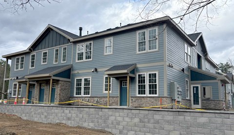 a large blue house with a stone retaining wall