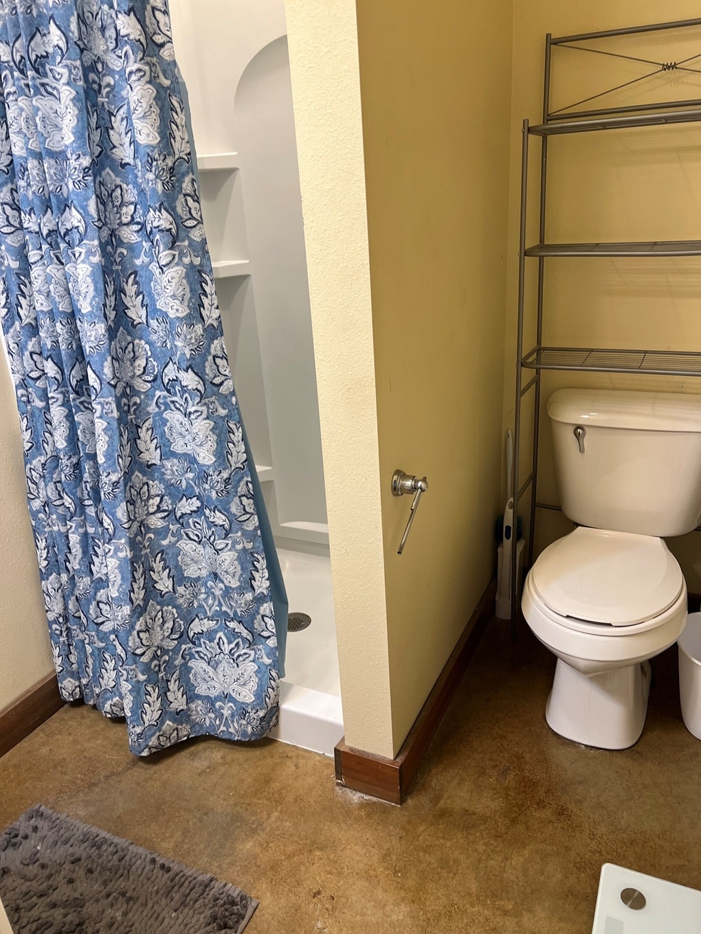 A white toilet sits next to a shower curtain in a bathroom.