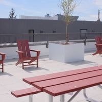 A red bench and chairs are on a patio.