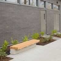 A grey building with a bench in front of it.