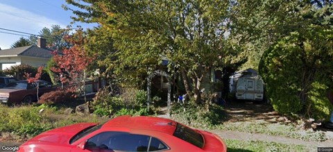 A red car is parked on the side of a street.