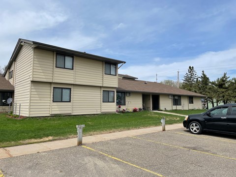 a yellow house with a black car parked in a parking lot