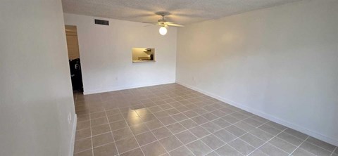 A spacious room with a ceiling fan and a small mirror on the wall.
