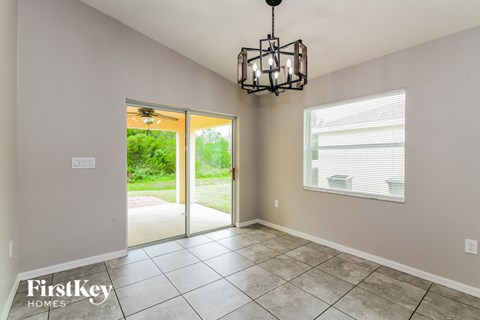 an empty dining room with a chandelier and a door to the yard