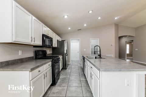 a large kitchen with white cabinets and black appliances