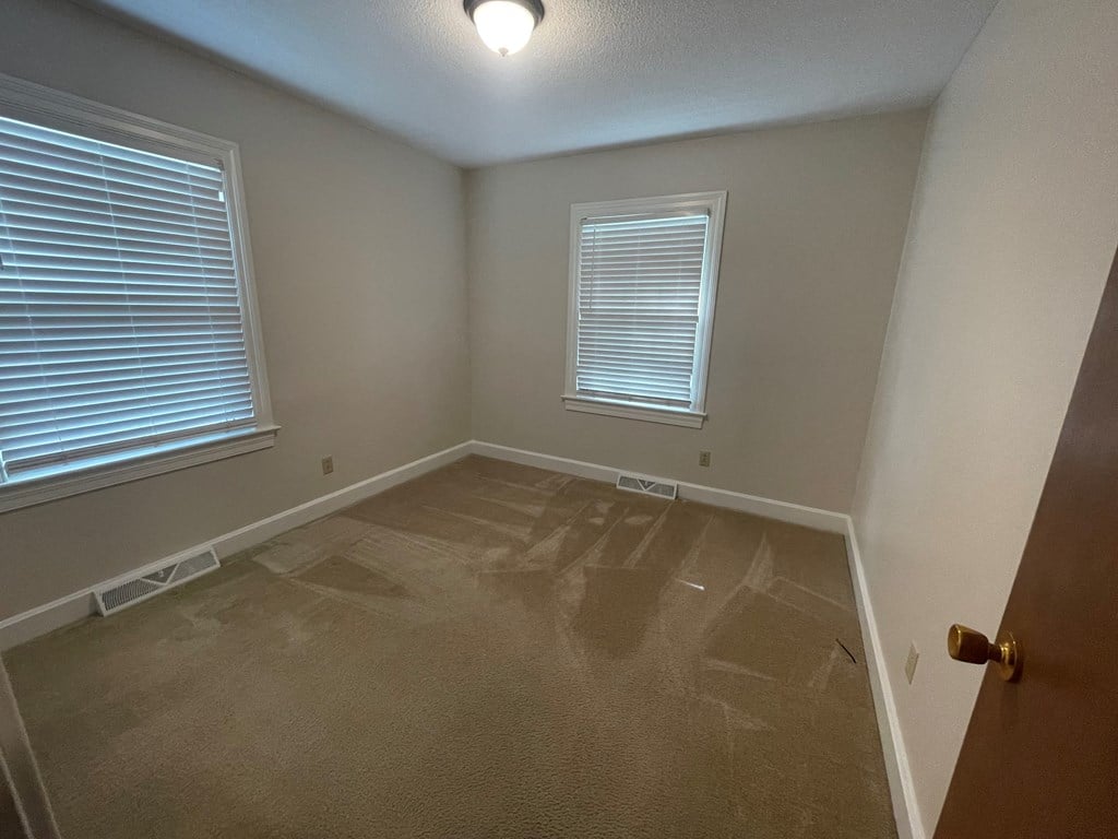 the interior of a empty room with a door and two windows