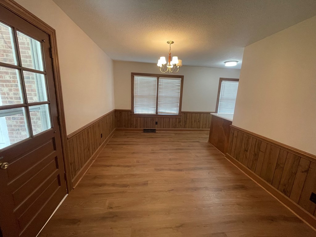 an empty dining room with wood paneling and a chandelier