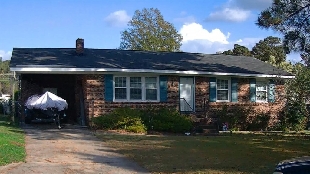 a brick house with a black roof and blue windows