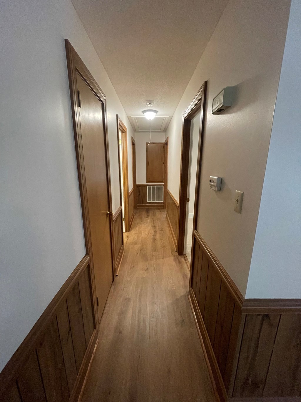 a hallway with wooden floors and doors and white walls