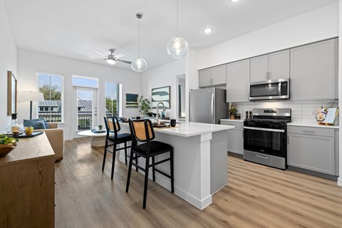 an open kitchen and dining area with a white counter top and stainless steel appliances