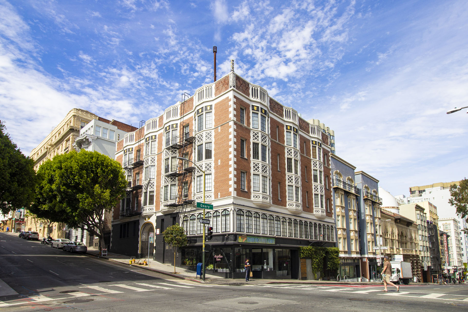 A street view of a large, multi-story building with a red brick facade and white trim.