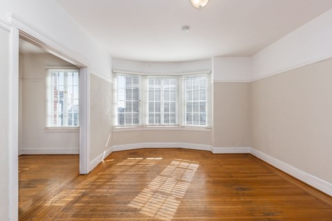 an empty living room with wood floors and a bay window