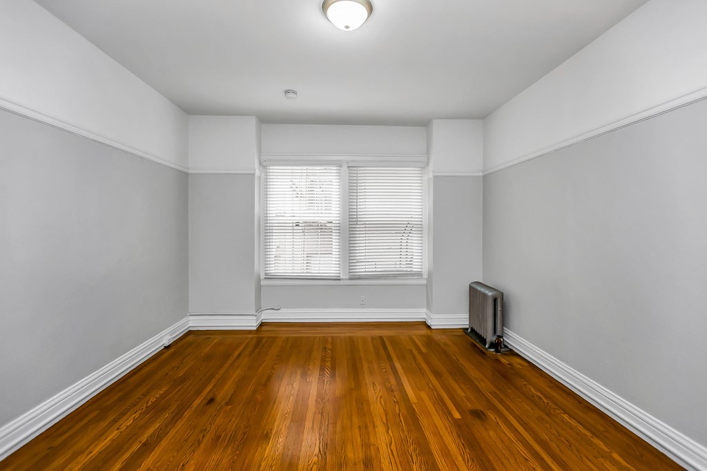 A room with wooden floors and a window with blinds.