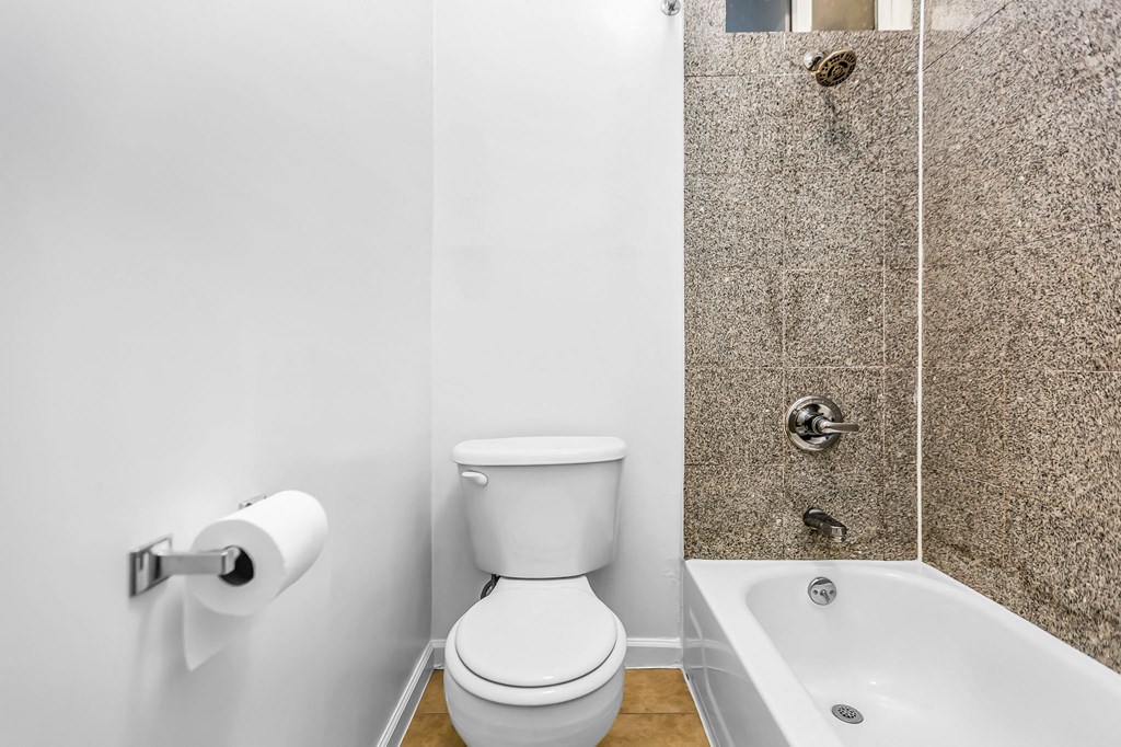 A white toilet sits next to a bathtub in a bathroom.