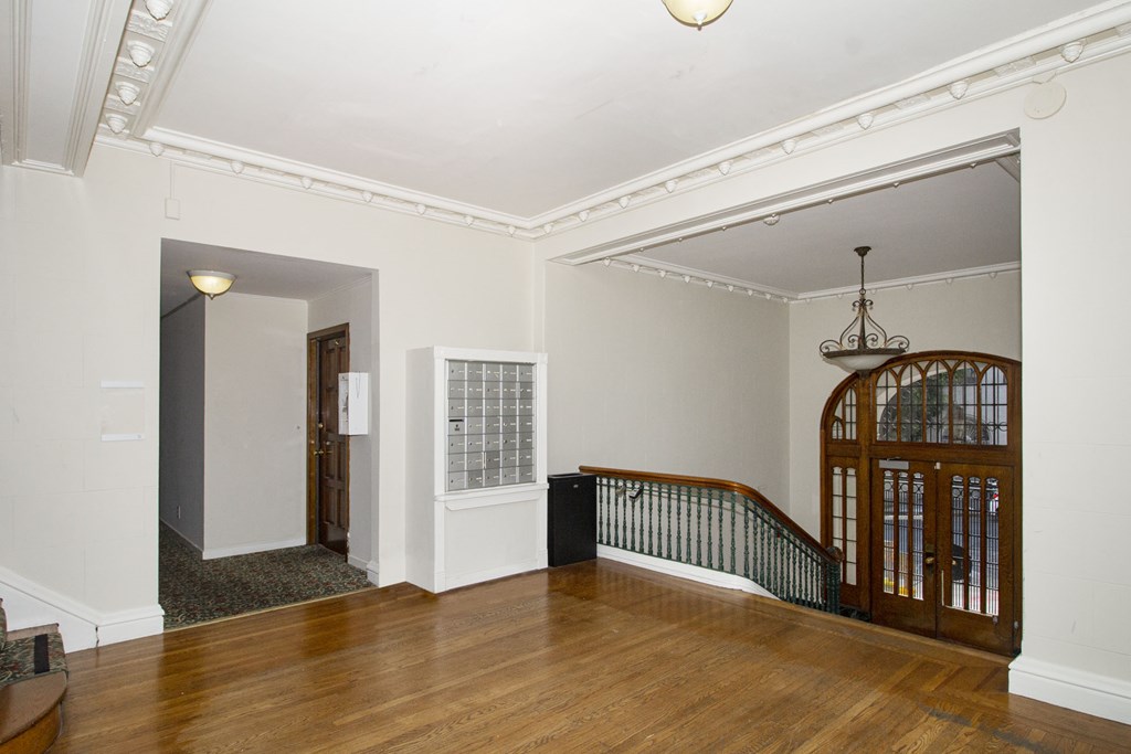 A room with a wooden floor and a staircase with a metal railing.
