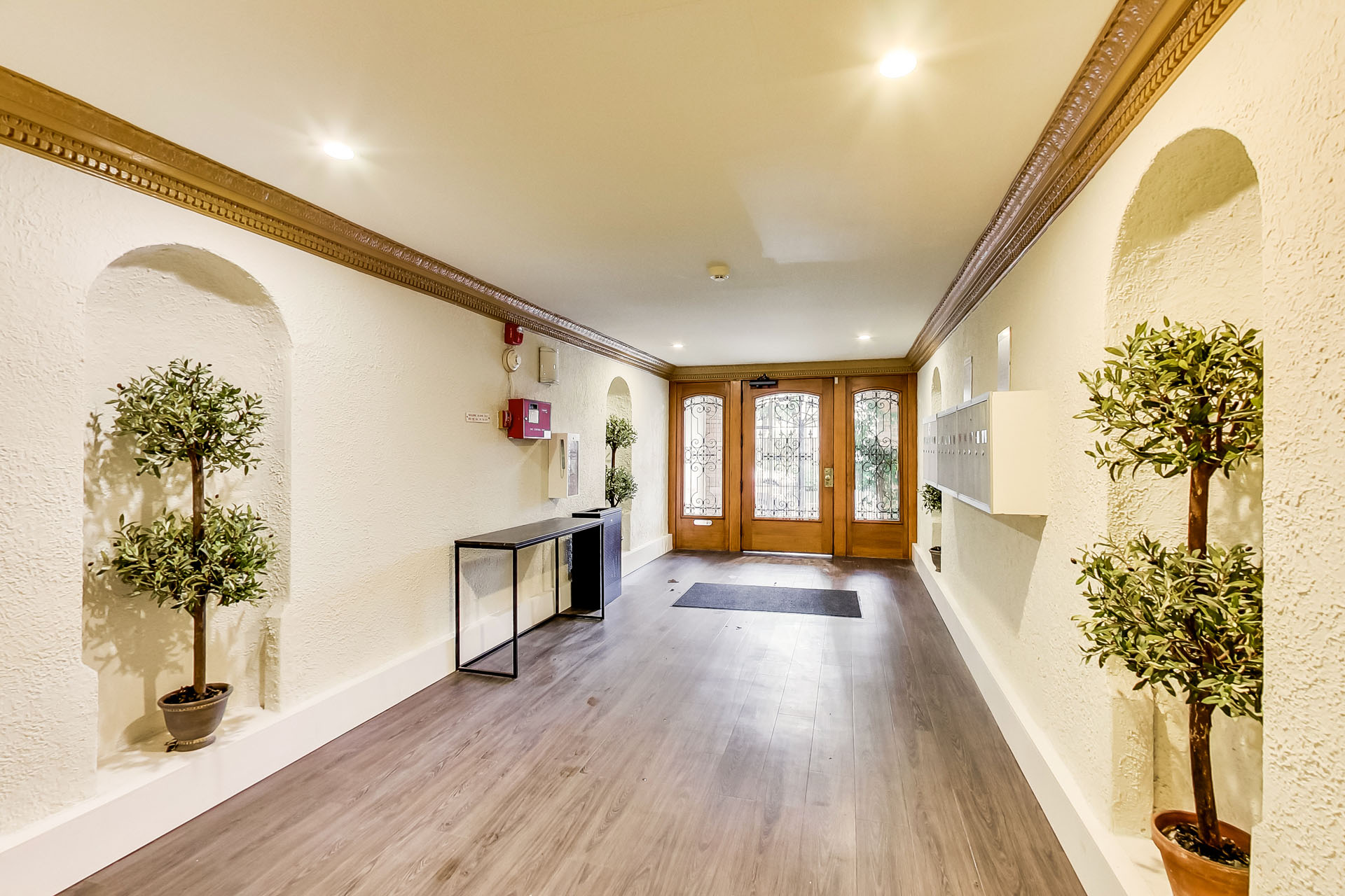 A hallway with wooden floors and white walls with arches.