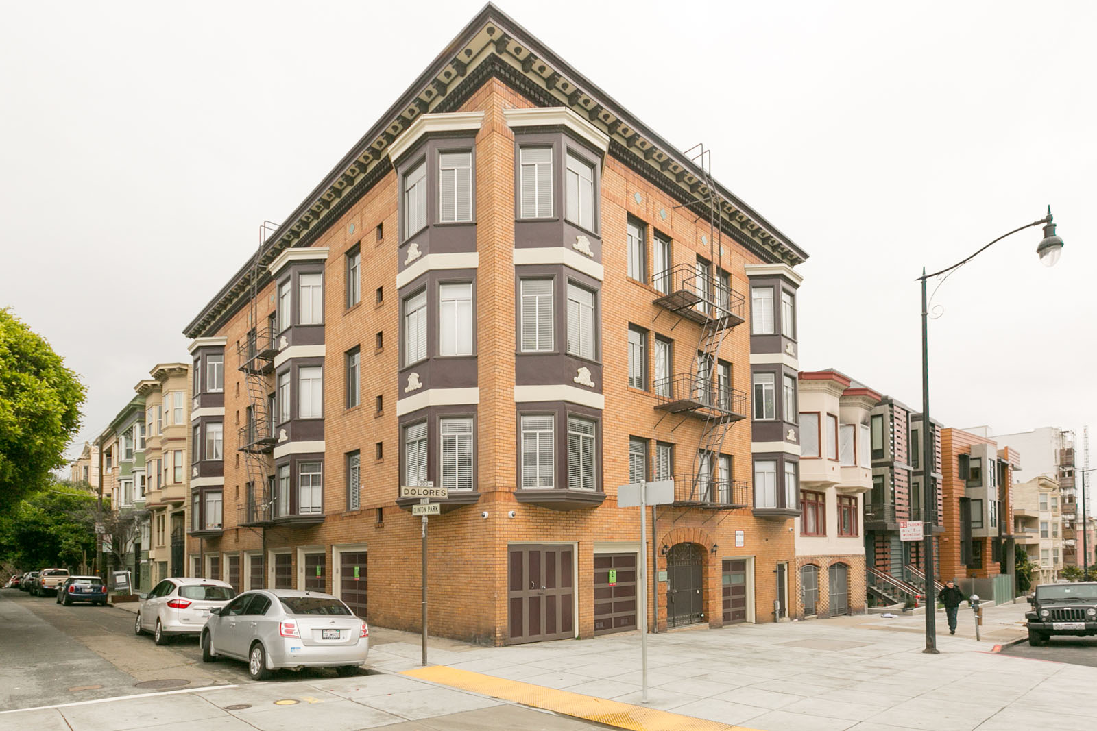 A street view of a multi-story building with cars parked in front.