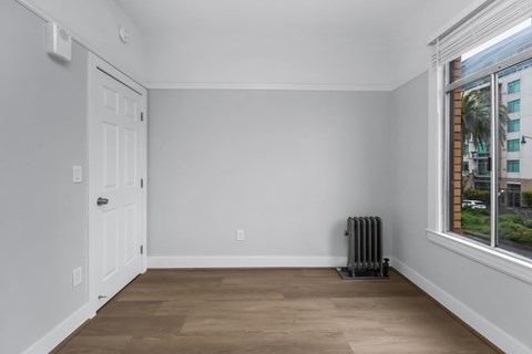 A room with a white door and a window with a view of a building outside.
