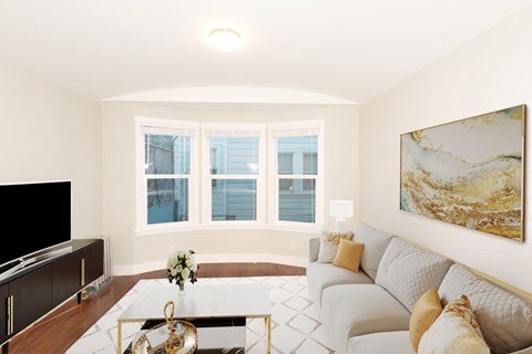 A living room with a white couch and a painting on the wall.
