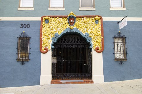 A blue building with a black door and a yellow decorative arch above it.