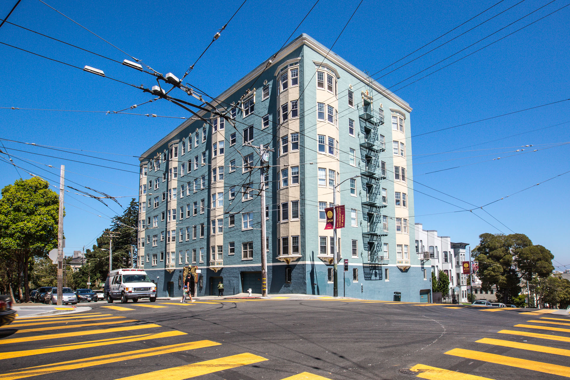 A street view of a blue building with a yellow crosswalk in front.