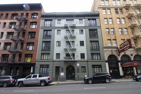 A street view of a hotel with cars parked in front.