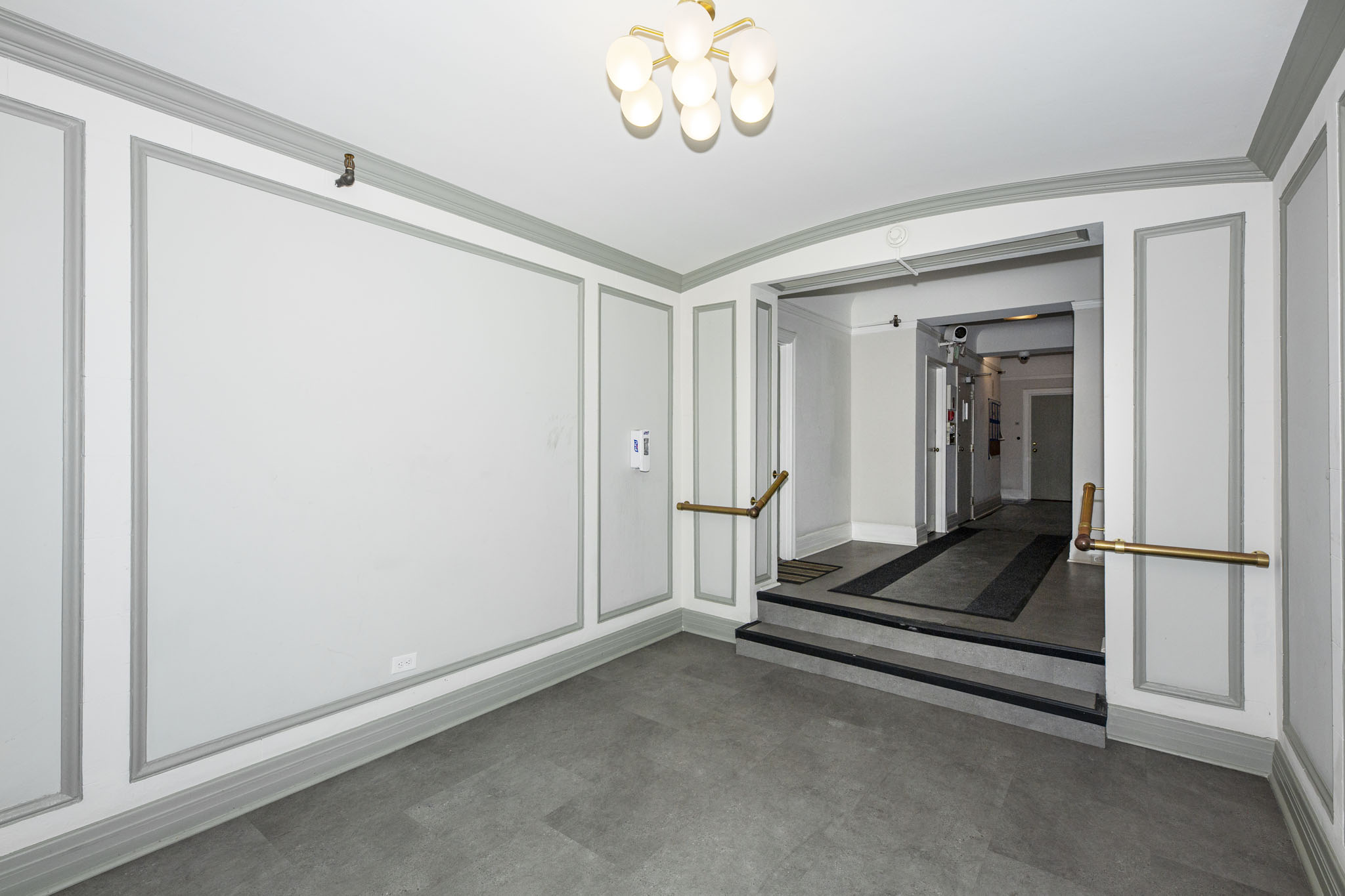 A hallway with a light on the ceiling and a door at the end.