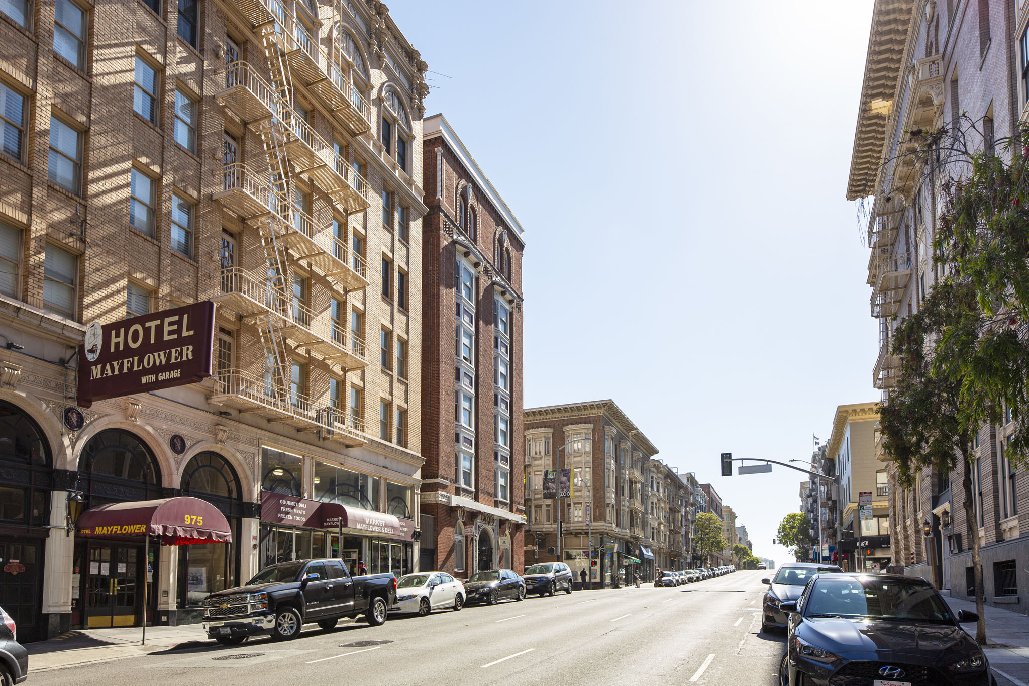 A street view of a city with cars parked on the side of the road and buildings on both sides.