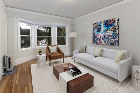 A living room with a white couch, a brown chair, and a painting on the wall.