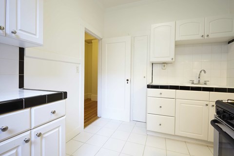 A kitchen with white cabinets and black countertops.