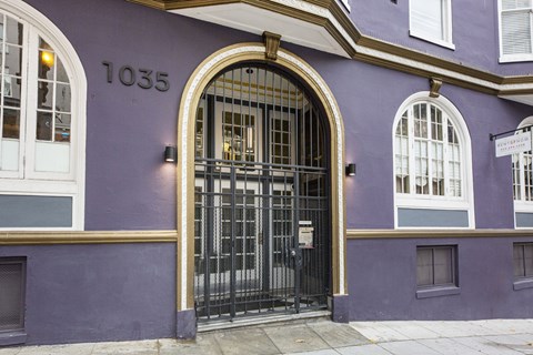 A purple building with a black gate and windows.