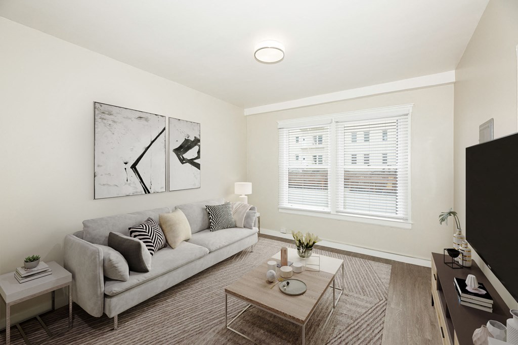 A living room with a grey couch, a coffee table, and a painting on the wall.