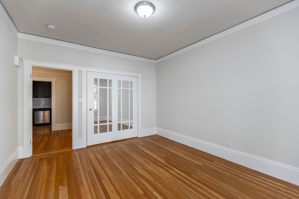 an empty living room with white walls and wood floors